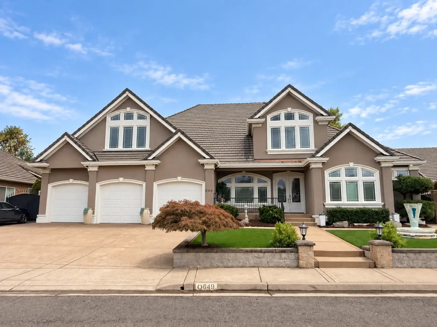 Two-story home with arched gable windows, a covered entry, and a three-car garage