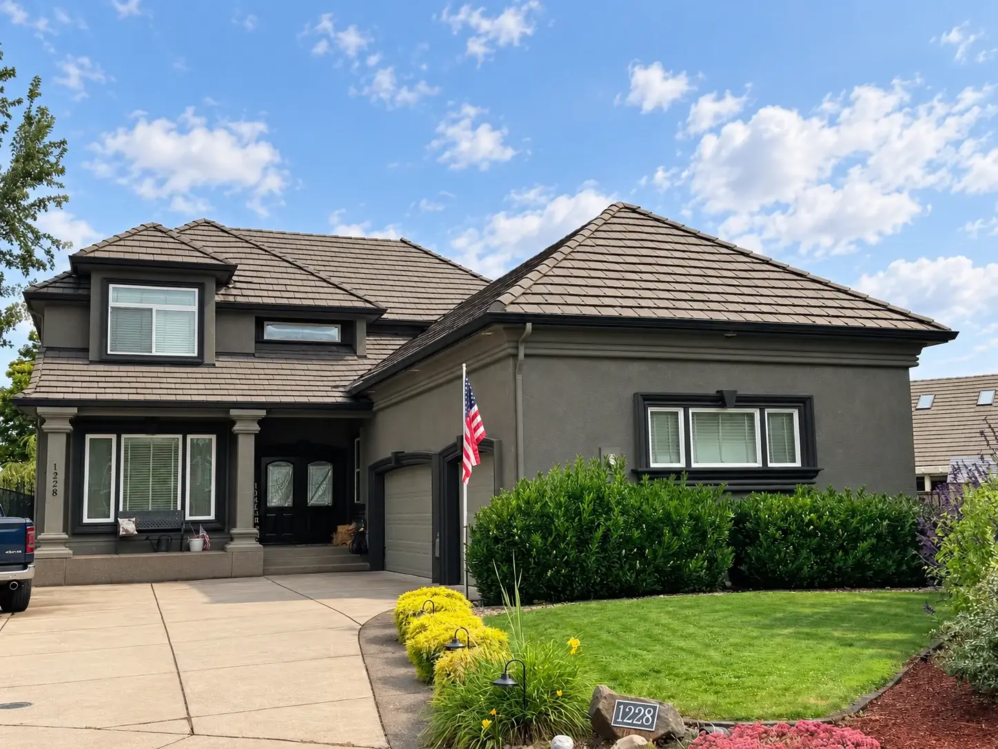 Two-story stucco home with a tile roof, stone entry columns, and a covered porch